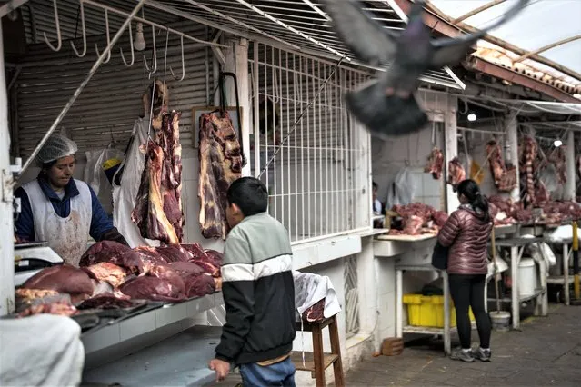 A meat vendor attends to a customer at a butcher stand in a food market in Cusco, Peru, Friday, January 27, 2023. The Defense Ministry said Thursday that the armed forces will support an effort by police to lift ongoing blockades on highways that the government says is causing shortages and price increases in certain parts of the country. (Photo by Rodrigo Abd/AP Photo)