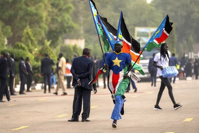 A man runs with flags next to the audience as they await the arrival of Pope Francis for a Holy Mass at the John Garang Mausoleum in Juba, South Sudan Sunday, Febriary 5, 2023. (Photo by Ben Curtis/AP Photo)