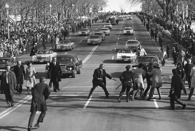 President Jimmy Carter and first lady Rosalynn watch, left, as police and Secret Service officials remove a spectator, right, who burst into the Inaugural Parade on Pennsylvania Avenue Thursday, January 20, 1977 in Washington. (Photo by AP Photo)