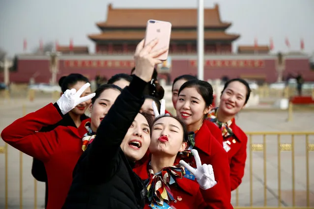 Ushers pose for pictures at the Tiananmen Square during the opening session of the National People's Congress (NPC) in Beijing, China March 5, 2018. (Photo by Thomas Peter/Reuters)