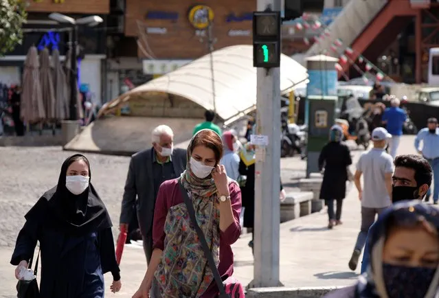 Iranian people wearing protective face masks cross an avenue in northern Tehran while the new coronavirus (COVID-19) disease rapid rising in Iran on October 4, 2020. Tehran Governor's office announced on Schools, libraries, mosques, and some other public places such as coffee shops, Holy shrines, and tea houses in Tehran would be closed for a week on Saturday to control the new coronavirus disease outbreak in Tehran but, streets were busy, Mosques and shrines were open, and people seem not to worry about the COVID-19, and Tehran was the same as its days before the virus outbreak. (Photo by Morteza Nikoubazl/NurPhoto via Getty Images)