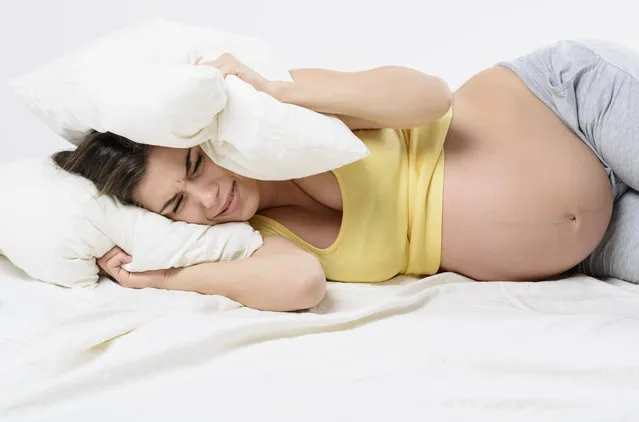 Stressed pregnant woman with sleeping problem laying down in a bed and weeping into two pillows. Woman with her pregnant belly naked. (Photo by MorePixels/Getty Images/iStockphoto)