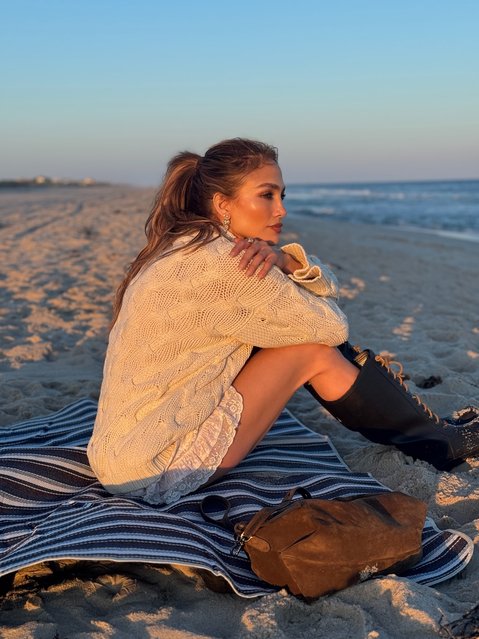 American singer, songwriter, actress, dancer and businesswoman Jennifer Lopez bundles up in a knit sweater and boots while lounging on the beach on September 29, 2025. (Photo by jlo/Instagram)