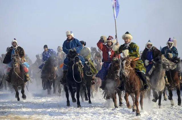 Contestants in traditional Mongolian costumes attend a horse race on a grassland covered in snow during a winter Naadam event in Hulun Buir, north China's Inner Mongolia Autonomous Region, December 23, 2014. Tens of thousands of locals attended the event which consisted of horse and camel racing, folk performance, fire worship ritual and so on, local media reported. (Photo by Reuters/Stringer)