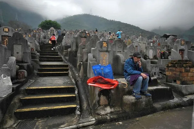 An elderly man has a cigarette at his relative's grave at the Diamond Hill Cemetery in Hong Kong on April 5, 2023 as people visit cemeteries to honour their ancestors during the annual Tomb Sweeping Day, known locally in Hong Kong as Ching Ming. (Photo by Peter Parks/AFP Photo)