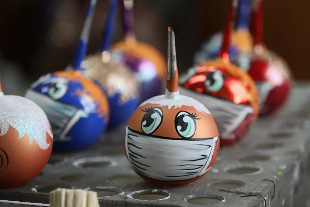 Christmas tree baubles wearing face masks on display at the Biryusinka factory in Krasnoyarsk, Russia on December 4, 2020. Biryusinka, a manufacturer of Christmas tree ornaments and toys, has launched the production of COVID-19 themed baubles. (Photo by Andrei Samsonov/TASS)