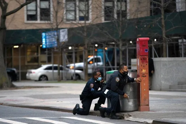 Police officers guard while a man is shooting outside the Cathedral Church of St. John the Divine in the Manhattan borough of New York City, New York, U.S., December 13, 2020. A man was shot and critically injured by police after he opened fire near crowds who had gathered to watch carol-singing outside a New York church. Witnesses reported no injuries. A spokeswoman for the New York Police Department said officers returned fire after the man started shooting. (Photo by Jeenah Moon/Reuters)