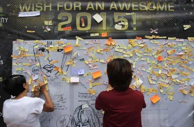 Onlookers write and post their New Year wishes on a wishing wall display at a mall in Quezon city, metro Manila December 31, 2014. The mall is gathering about 50,000 wishes, which will be used as confetti for its New Year celebrations alongside festive fireworks. (Photo by Romeo Ranoco/Reuters)