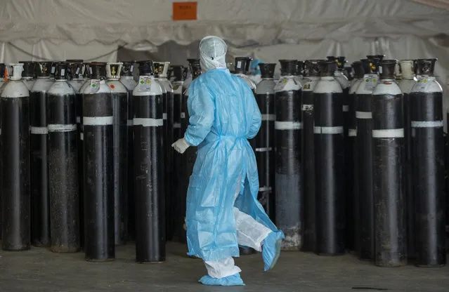 A health worker in a protective suit runs past oxygen cylinders in a makeshift emergency unit at Steve Biko Academic Hospital in Pretoria, South Africa, Monday, January 11, 2021, which is battling an ever-increasing number of Covid-19 patients. (Photo by Themba Hadebe/AP Photo)