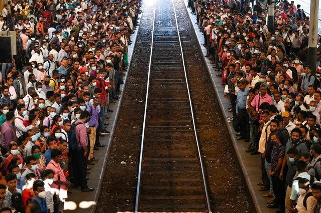 Commuters wait to board a train at the Fort railway station during a nationwide strike in Colombo on March 15, 2023. Sri Lanka deployed armed troops as trade unions crippled hospitals, ports and banks March 15 to protest against high income taxes imposed as a precondition for a crucial IMF bailout. (Photo by Ishara S. Kodikara/AFP Photo)