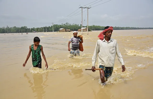 Villagers wade through a flooded road at a village in Hojai district, in the northeastern state of Assam, India, June 17, 2018. (Photo by Anuwar Hazarika/Reuters)
