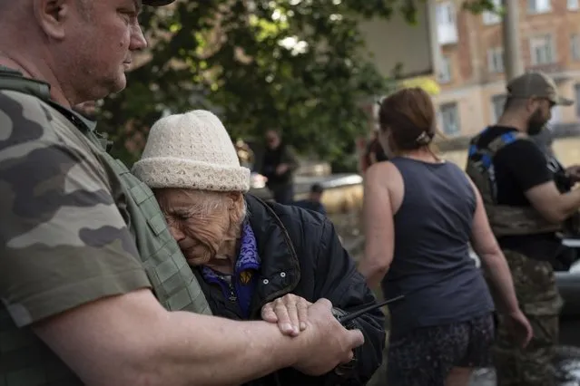 A woman cries as she is evacuated from a flooded neighborhood in Kherson, Ukraine, Wednesday, June 7, 2023 after the Kakhovka dam was blown up. Residents of southern Ukraine braced for a second day of swelling floodwaters on Wednesday as authorities warned that a Dnieper River dam breach would continue to unleash pent-up waters from a giant reservoir. (Photo by Roman Hrytsyna/AP Photo)