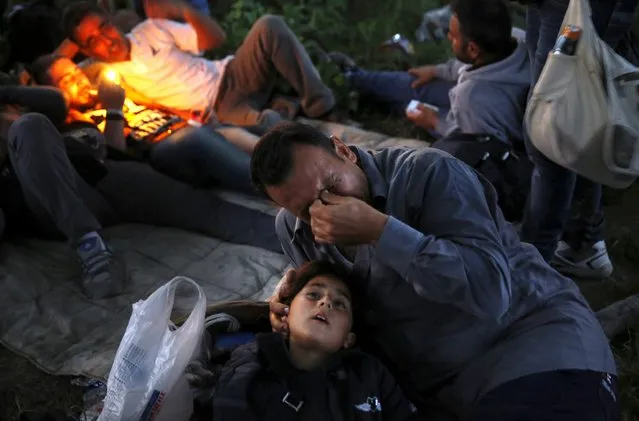 Kurdish Syrian refugee Sahin Serko cries next to his seven-year-old daughter Ariana minutes after crossing the border into Macedonia along with another 45 Syrian refugees, near the Greek village of Idomeni in Kilkis prefecture May 14, 2015. (Photo by Yannis Behrakis/Reuters)