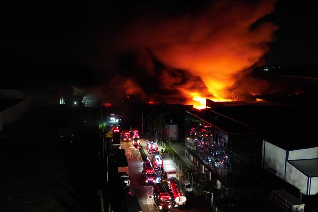 This aerial view shows fire trucks heading to the fire after an explosion in an industrial area of Ezeiza, Buenos Aires province, Argentina on November 15, 2025. Powerful explosions rocked an industrial area and ignited a fire south of Buenos Aires on the night of November 14, 2025, officials said, with at least 22 people sent to the hospital. (Photo by Luis Robayo/AFP Photo)