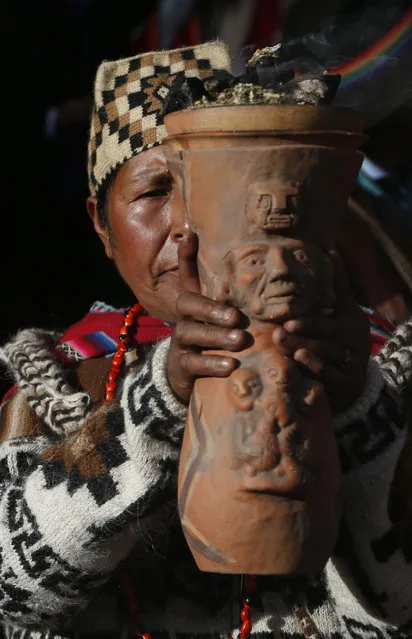 An Andean religious leader holds an urn with burning incense in a procession of the Bolivian deity statuette “illa of Ekeko” as it is driven to the Alasitas Fair, in which Ekeko is the central figure, in La Paz, Bolivia, Saturday, January 24, 2015. (Photo by Juan Karita/AP Photo)