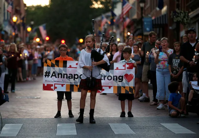 People line the street as a woman plays “Amazing Grace” on a bagpipe during a candlelight vigil in downtown Annapolis to honor the five people who were killed inside the Capital Gazette newspaper the day before in Annapolis, Maryland, U.S. June 29, 2018. (Photo by Leah Millis/Reuters)
