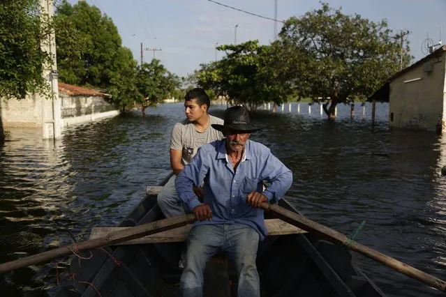 Victor Ferreira, who is displaced by flooding, rows his boat through the streets of his Jukyty neighborhood in Asuncion, Paraguay, Wednesday, December 23, 2015. The Paraguay River is at its highest level since 1984 and threatening the poor districts that surround the capital, forcing about 100,000 people to shelters. (Photo by Jorge Saenz/AP Photo)