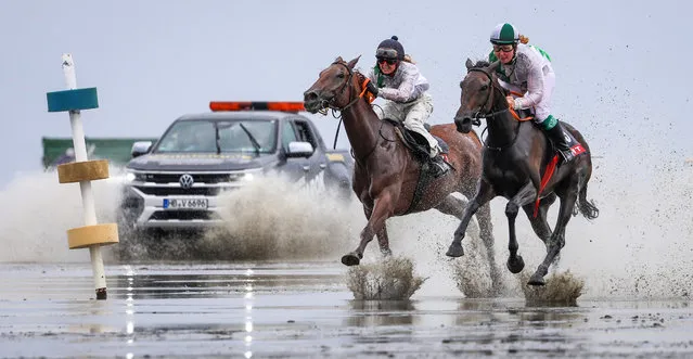 Gallop riders compete in the mudflats of the Elbe estuary during the Duhner Wattrennen horse racing day in Cuxhaven, northern Germany, on July 15, 2023. The races take place at low tide, making them a rare opportunity to see equestrian competitions on the seabed. (Photo by Focke Strangmann/AFP Photo)