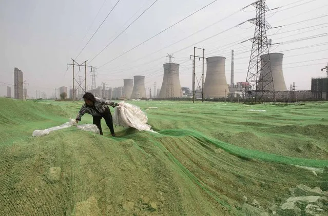 A labourer collects plastic bags on a dust screen covering construction waste near a power plant in Zhengzhou, Henan province in this July 15, 2014 file photo. China Power Investment Corp is merging with the State Nuclear Power Technology Corp, as Beijing drives consolidation in its rapidly expanding nuclear power sector with the aim of eventually exporting reactors. (Photo by Reuters/Stringer)