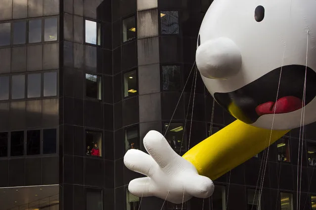People watch as the Diary of a Wimpy Kid balloon makes its way across Sixth Avenue during the Macy's Thanksgiving Day Parade, in New York, Thursday, November 24, 2016. (Photo by Andres Kudacki/AP Photo)