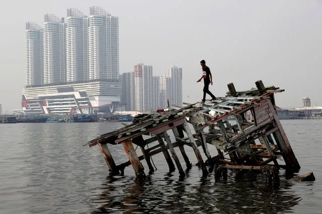 A youth walks on the wreckage of a wooden boat, as smog covers North Jakarta, Indonesia, July 26, 2018. (Photo by Reuters/Beawiharta)