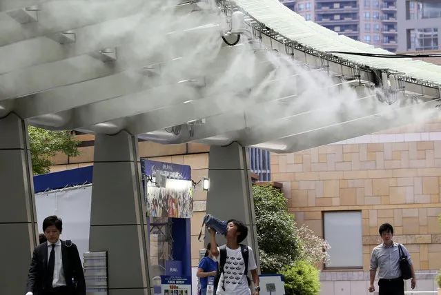 People cool down under the cooling mist spot in Tokyo, Monday, July 23, 2018. Searing hot temperatures are forecast for wide swaths of Japan and South Korea in a long-running heat wave. The mercury is expected to reach 39 degrees Celsius (102 degrees Fahrenheit) on Monday in the city of Nagoya in central Japan and reach 37 (99 F) in Tokyo. (Photo by Koji Sasahara/AP Photo)