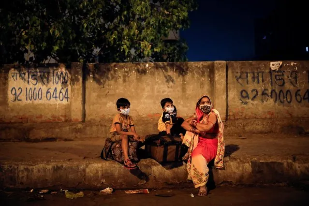 A migrant worker's family waits at a bus station to board a bus to return to their village after Delhi government ordered a six-day lockdown to limit the spread of the coronavirus disease (COVID-19), in Ghaziabad on the outskirts of New Delhi, India, April 19, 2021. (Photo by Adnan Abidi/Reuters)