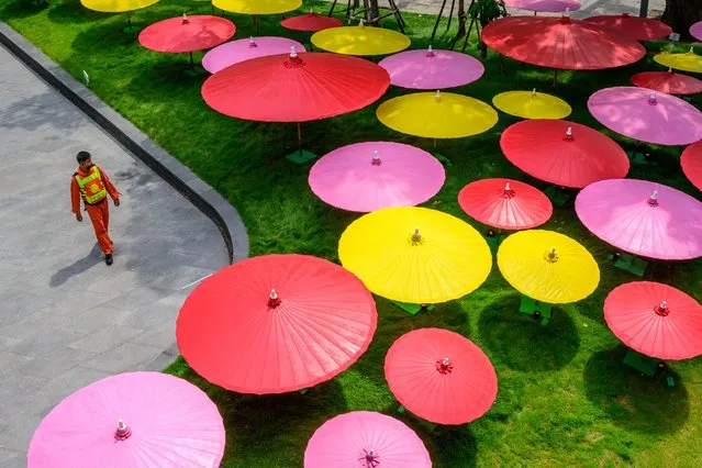 A security guard walks past a decorative installation made of colorful paper umbrellas outside a shopping mall in Bangkok on March 30, 2021. (Photo by Mladen Antonov/AFP Photo)