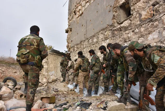 Syrian pro-government troops hold a position in Aleppo's eastern Karm al-Jabal neighborhood as they advance towards al-Shaar neighbourhood on December 5, 2016 during their offensive to retake Syria's second city. The Syrian Observatory for Human Rights said the advances of the Syrian and allied forces left the large Shaar neighbourhood encircled by government forces and in danger of falling from rebel control. With the capture of Shaar, the army would hold 70 percent of east Aleppo, four years after rebels first seized it. (Photo by George Ourfalian/AFP Photo)