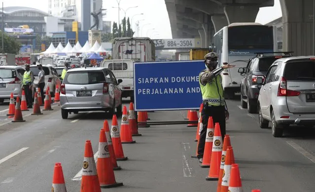 Indonesian police guard at a checkpoint during the imposition of large-scale restriction to curb the spread of the coronavirus on a toll road in Cikarang, West Java, Indonesia, Thursday, May 6, 2021. Indonesia is prohibiting travel during the popular homecoming period to celebrate Eid al-Fitr. The ban started Thursday and will last for 12 days, exempting only civil servants, police and military officers, and those who need to travel for work. (Photo by Achmad Ibrahim/AP Photo)