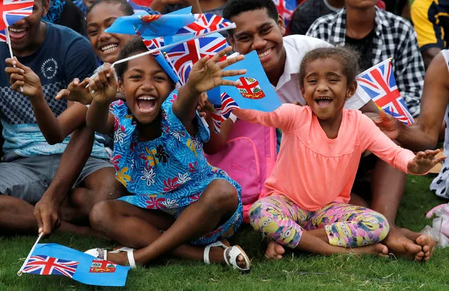 Children smile and wave flags as Britain's Prince Harry and Meghan, Duchess of Sussex, arrive in Suva, Fiji, October 23, 2018. (Photo by Phil Noble/Reuters)