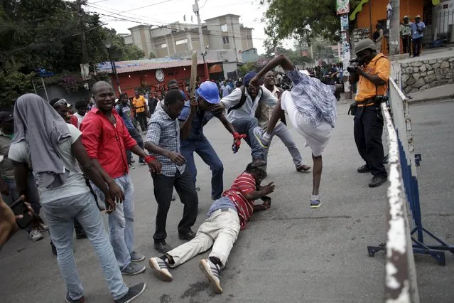 Protesters, who were mocking National Police officers (not pictured), simulate a beating during a demonstration against the electoral process in Port-au-Prince, Haiti, January 22, 2016. Haiti postponed a U.S.-backed presidential election as violent protests erupted on Friday after the opposition candidate vowed to boycott the vote over alleged fraud. (Photo by Andres Martinez Casares/Reuters)