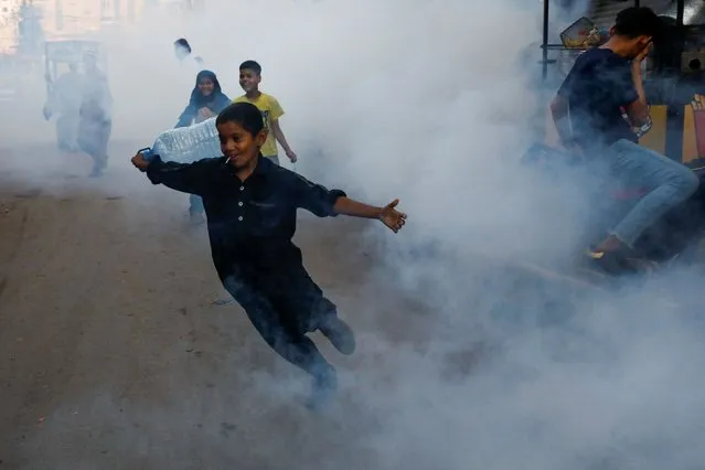 A boy reacts as he runs amid the fumigation vapour cloud, that is being sprayed to stem the spread of dengue virus, in Karachi, Pakistan on September 13, 2023. (Photo by Akhtar Soomro/Reuters)