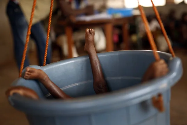 A young child lies in a bucket to be weighed by nurses in Bangui, Central African Republic, on February 11, 2016. The United Nations World Food Program estimates that nearly half the country - 2.5 million people - are facing hunger as more than two years of violence have severely disrupted the country's agriculture and health care sectors. (Photo by Jerome Delay/AP Photo)