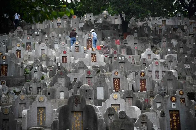 People tend to graves in a cemetery in Diamond Hill in Hong Kong on October 23, 2023, during the Chung Yeung Festival, also known as the Double Ninth Festival, where people honour their ancestors. (Photo by Peter Parks/AFP Photo)