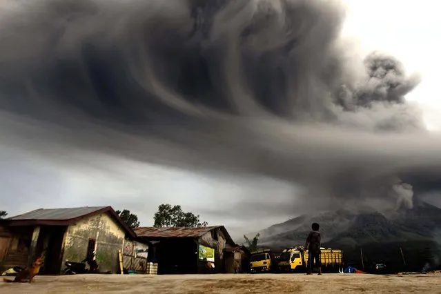 A woman in Sibintun village looks on as Mount Sinabung spews ash. (Photo by Roni Bintang/Reuters)