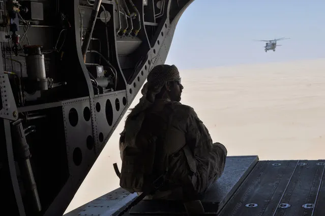 In this Monday, September 14, 2015 file photo, an Emirati soldier stands guard out the rear gate of a Chinook military helicopter, escorted by a Blackhawk helicopter, traveling from Saudi Arabia to Yemen. Saudi Arabia's offer to put boots on the ground to fight Islamic State in Syria is as much about the kingdom's growing determination to flex its military might as it is about answering U.S. calls for more help from Mideast allies. (Photo by Adam Schreck/AP Photo)