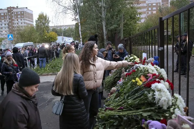 People gather to lay flowers, put toys and light candles in memory of victims of the shooting at school No. 88 in Izhevsk, Russia, Monday, September 26, 2022. Authorities say a gunman has killed 15 people and wounded 24 others in a school in central Russia. According to officials, 11 children were among those killed in the Monday morning shooting in School No. 88 in Izhevsk, a city 960 kilometers (600 miles) east of Moscow in the Udmurtia region. (Photo by Sergei Kuznetsov/AP Photo)