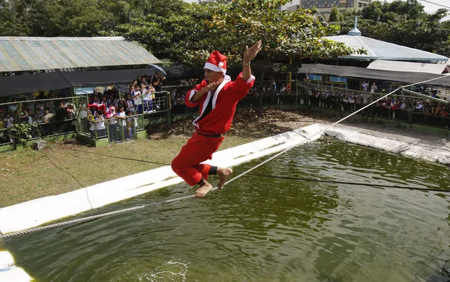 Jonald Libres, 28, walks on a tight rope over live crocodiles while wearing a Santa Claus costume as part of performances for the Christmas Yuletide season at a crocodile farm in Pasay city, metro Manila December 12, 2013. (Photo by Romeo Ranoco/Reuters)