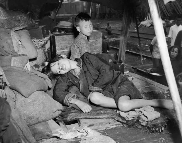 So tired that he can't keep his eyes open, one refugee child goes asleep sitting up straight while the other, ill from lack of food, lolls back on the sacks carrying the family belongings and tries to get some rest in China, January 11, 1944. Soon the family will be on the move again, in a truck or railroad car, or even on their own feet. (Photo by Frank Cancellare/AP Photo)