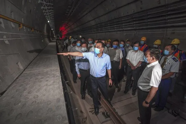 In this August 18, 2021, photo released by Xinhua News Agency, Chinese Premier Li Keqiang, left, wearing a face mask, visits the tunnel of subway line 5 in Zhengzhou city in central China's Henan province. Li vowed to hold officials accountable over mistakes during recent floods that led to the deaths of hundreds of people in a major provincial capital, including 14 who were trapped when the city’s subway system was inundated. (Photo by Rao Aimin/Xinhua via AP Photo)