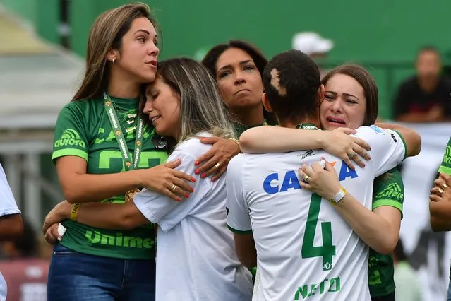 Brazilian Chapecoense footballer Helio Neto (front- R), a survivor of the LaMia airplane crash in Colombia, embraces relatives of players who died in an airplane crash, at the Arena Conda stadium in Chapeco, Santa Catarina state, in southern Brazil on January 21, 2017, before a friendly match against Palmeiras – Brazilian Champion 2016. .Most of the members of the Chapocoense football team perished in a November 28, 2016 plane crash in Colombia. (Photo by Nelson Almeida/AFP Photo)