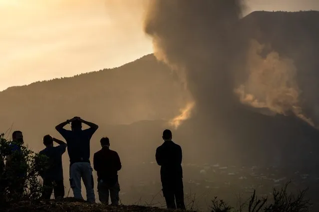 Residents look from a hill as lava continues to flow from an erupted volcano, on the island of La Palma in the Canaries, Spain, Friday, September 24, 2021. A volcano in Spain‚ Canary Islands continues to produce explosions and spew out lava, five days after it erupted. Two rivers of lava continue to slide slowly down the hillside of La Palma on Friday. (Photo by Emilio Morenatti/AP Photo)