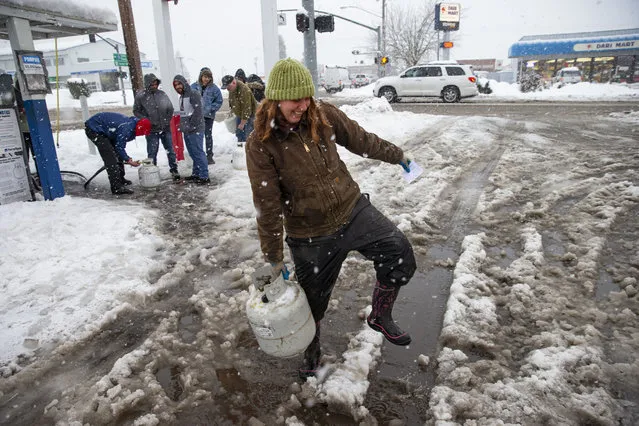 Lisa Laroe of Creswell, carries a propane bottle to her vehicle as other people lineup at the 76 gas station Tuesday, February 26, 2019, in Creswell, Ore. The station has had a steady stream of people all day filling gas tanks and propane bottles as another snow storm moves through the Willamette Valley. (Photo by Chris Pietsch/The Register-Guard via AP Photo)