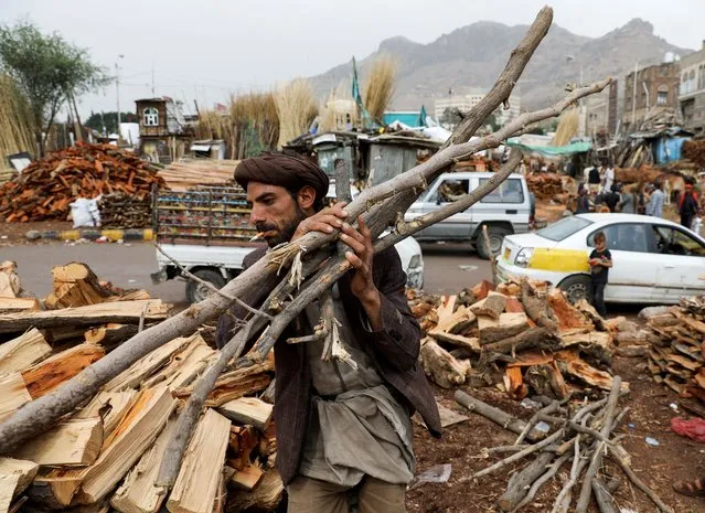 A vendor carries wood at a firewood market in Sanaa, Yemen, July 17, 2021. (Photo by Khaled Abdullah/Reuters)