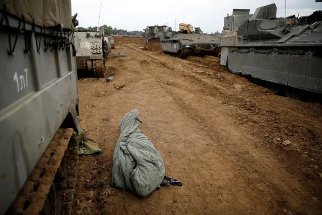 An Israeli soldier sleeps in a sleeping bag next to Israeli armoured military vehicles near the border with Gaza, in southern Israel on March 29, 2019. (Photo by Amir Cohen/Reuters)