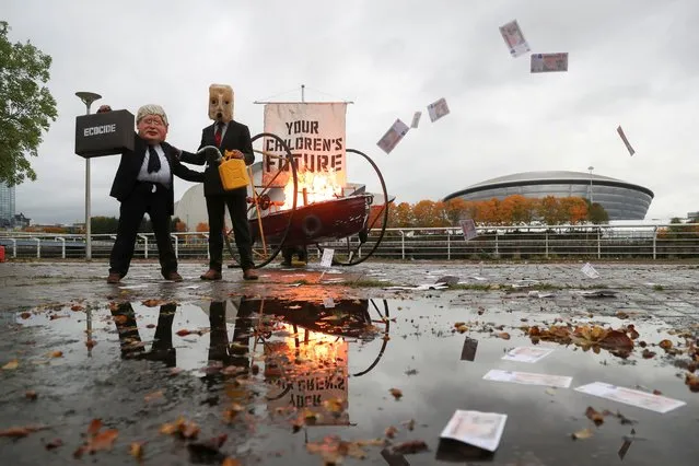 Ocean Rebellion activists dressed as Boris Johnson and “Oil head” set fire to the sail of a small boat next to the River Clyde, opposite the  Scottish Event Campus, where the COP26 will take place, in Glasgow, Scotland, Britain, October 27, 2021. (Photo by Russell Cheyne/Reuters)
