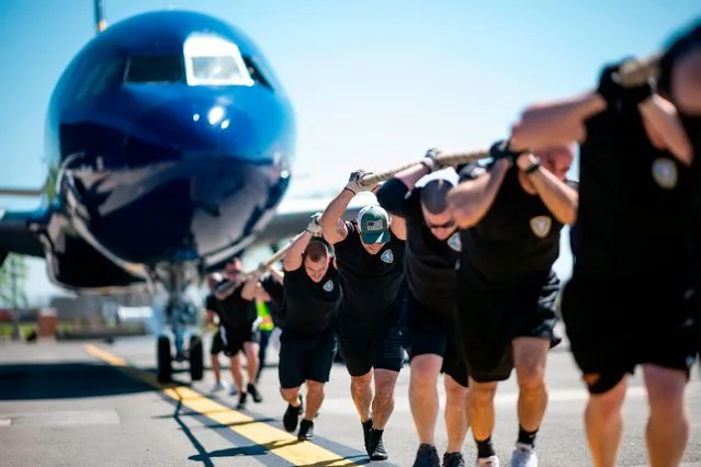 Competitors pull a JetBlue A320 aircraft as they compete in a “Plane Pull” at John F. Kennedy International Airport on May 21, 2019 in New York. Law enforcement officers from communities in New York and the United Kingdom competed to raise Awareness for the “Joining Against Cancer in Kids” (JACK) Foundation. The team which pulled the aircraft 100 feet (30.5 meters) the fastest was the winner. (Photo by Johannes Eisele/AFP Photo)