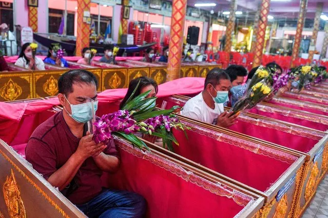 Devotees pray as they lie down inside coffins to get rid of bad luck and to reborn again for a fresh start in the New Year at a temple in Nonthaburi, in the outskirt of Bangkok, Thailand on January 2, 2023. (Photo by Chalinee Thirasupa/Reuters)