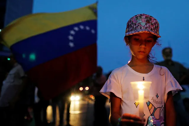 A girl holds a candle while participating in a candlelight vigil held for victims of recent violent in Caracas, Venezuela May 5, 2019. (Photo by Ueslei Marcelino/Reuters)